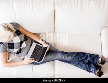 Draufsicht der Frau liegend auf der weißen Couch und einen Laptop verwenden. Querformat. Stockfoto
