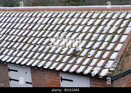 Schnee und Hagel Steinen auf Flachdachziegel Dach von einem Nebengebäude. Stockfoto