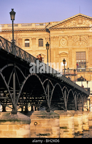 LIEBHABER, EIN PAAR UMARMT, PONT DES ARTS MIT DEM LOUVRE IM HINTERGRUND, PARIS 6. ARRONDISSEMENT, PARIS (75), FRANKREICH Stockfoto