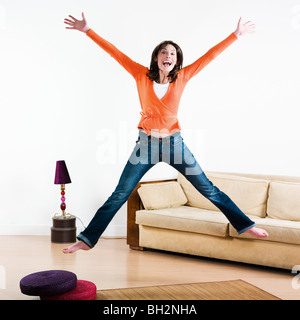 glückliche Frau in einem Wohnzimmer springen Stockfoto