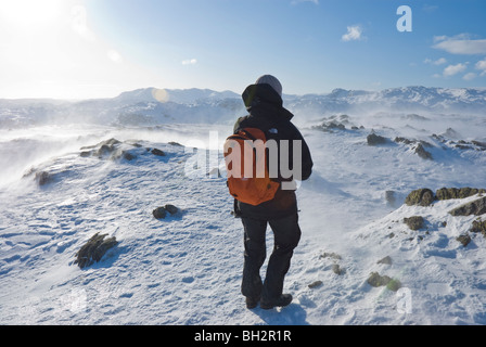 Einsame weibliche Walker mit Winterkleidung und Rucksack auf Schnee bedeckt Stahl fiel in den Cumbrian Lake District. Stockfoto