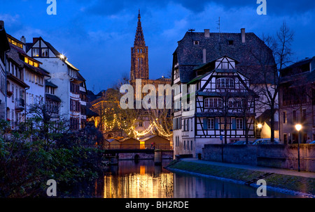 Blick auf Kanal, alte Gebäude im Viertel petite France mit Kathedrale von Straßburg in Ferne bei Nacht, Frankreich. Stockfoto