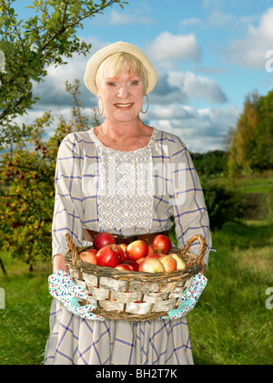 Reife Frau mit Korb Äpfel Stockfoto