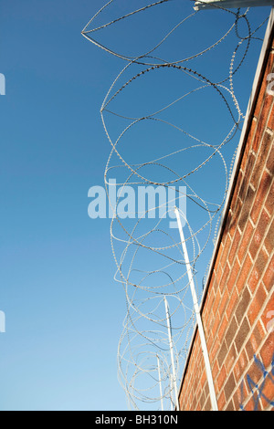 gewickelten Stacheldraht auf einer gemauerten Wand Stockfoto
