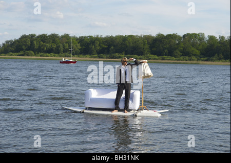 Junger Mann stand vor einer Couch montiert, Surfbretter mitten im See, Blick in Ferne Stockfoto