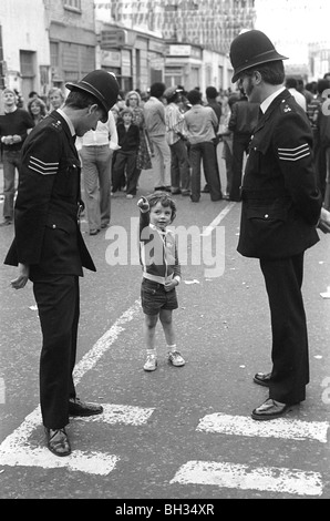 Polizei aus den 1970er Jahren mit dem kleinen Jungen Notting Hill West London. Gemeindepolizisten sind auf dem Schlag. 1970 UK HOMER SYKES Stockfoto