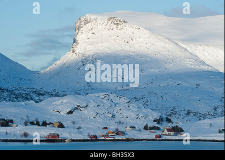 Häusern, einem kleinen Dorf unter schneebedeckten Bergen. Winterlandschaft aus Krystad, Lofoten-Inseln, Nord-Norwegen Stockfoto