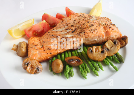 Eine Mahlzeit mit gebratenem Lachssteak mit gedünstetem Spargel, gebratenen Pilzen und frischen Tomaten Stockfoto