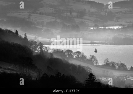 Mit Blick auf einen nebligen Windermere aus Kirkstone Pass über Ambleside, als ein Boot segelt auf dem See. Stockfoto