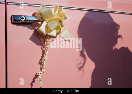 Hochzeit-Bänder an der Seite eine rosa Brautauto mit dem Schatten der Braut geworfen auf dem Auto. Stockfoto