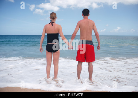 Junges Paar Hand in Hand am Strand mit Blick bis zum Horizont Stockfoto