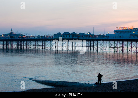 Ein Fotograf fotografiert Brighton Pier vom Strand am Abend. Brighton East Sussex UK Winter. Stockfoto