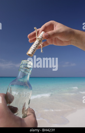 Ein Mann Hände halten eine Nachricht in einer Flasche auf einem einsamen tropischen Strand Stockfoto