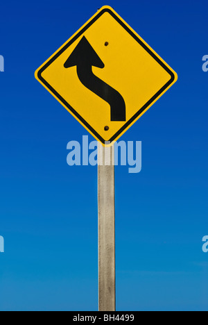 Ein Schild zeigt eine Kurve in der Strasse. Isoliert auf einem abgestuften blauen Hintergrund. Stockfoto