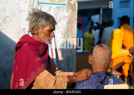 Straße Barbier geben einen traditionellen Haarschnitt in Pushkar. Stockfoto