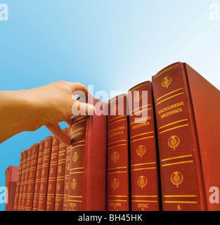 Nahaufnahme der Hand einer Person, die eine Reihe von Enzyklopädie Britannica Bücher ein Volume auswählen. Stockfoto