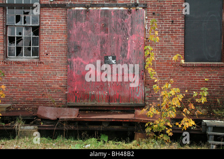 Fassade aus einem desolaten Gebäude mit zerbrochenen Fenstern und alte Tür mit Resten von Farbe in Lincoln. Stockfoto