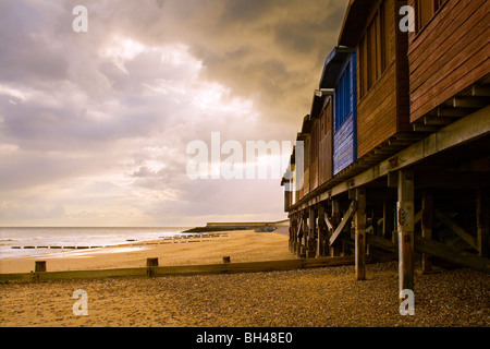Strandhütten auf Stelzen an einem Sandstrand direkt am Meer bei Frinton-on-Sea. Stockfoto