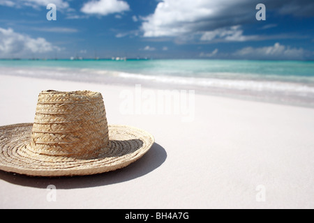 Auf einem weißen tropischen einsamen Sandstrand liegen Stroh Sonnenhut Stockfoto