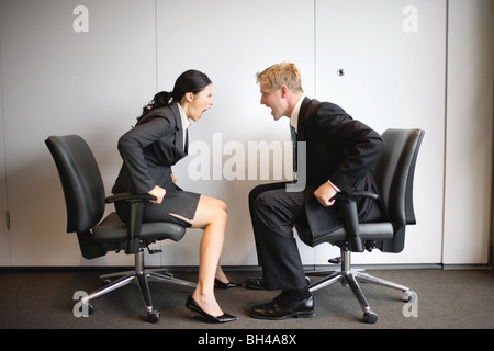 Zwei Kollegen einander anschreien, sitzen auf Bürostühlen Stockfoto