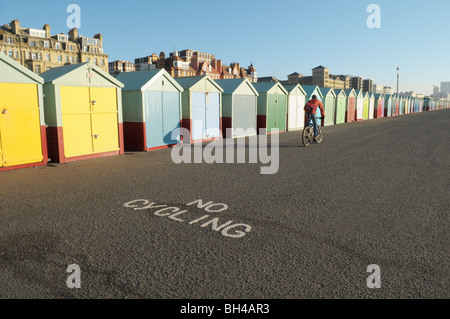 Ein Radfahrer sein Fahrrad an Hove und Brighton Strandpromenade vorbei Strandhütten und ein "kein Radfahren" Zeichen Stockfoto