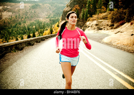 Eine sportliche Frau, Joggen auf einer verlassenen Straße an einem schönen Herbsttag. Stockfoto