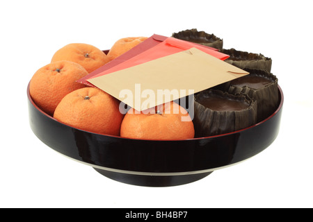 Chinesisches Neujahr-Reiskuchen, Mandarin-Orangen und roten Pakete auf weißem Hintergrund Stockfoto