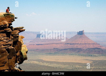 Ein junger Mann sitzt auf einem Felsen während des Essens einer oranges auf der Porcupine Rim Trail in Moab, Utah. Stockfoto