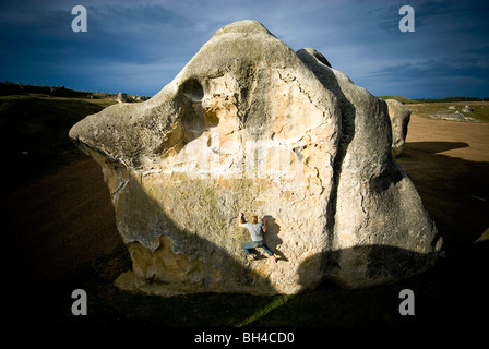 Ein junger Mann durchläuft einen Felsblock im Elephant Rocks, Neuseeland. Stockfoto