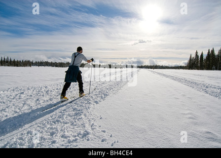 Ein junger Mann Langlaufski auf einem verschneiten Trail in Safari Lake, Alaska. Stockfoto