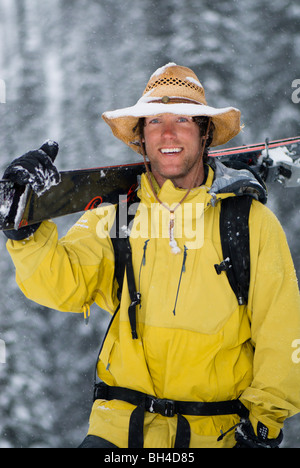 Ein Mann lächelt einen verschneiten Cowboy Hut und seine Skier tragen. Stockfoto