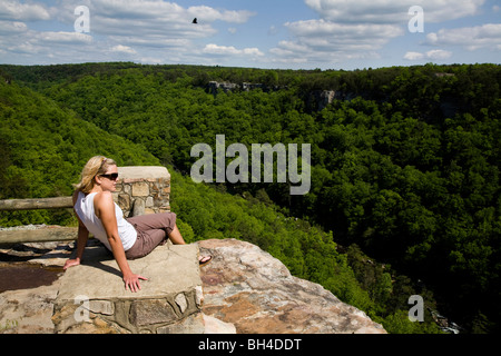 Eine junge, blonde Frau genießt die Aussicht über eine tiefe Schlucht, bedeckt mit Bäumen in Alabama, USA. Stockfoto