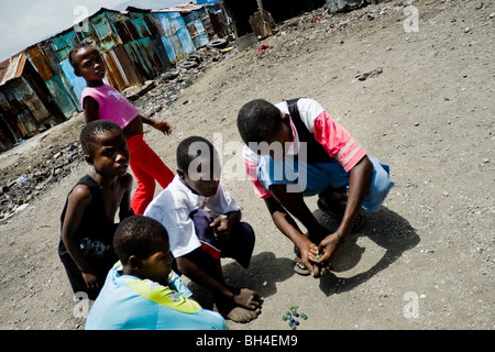 Haitianische Kinder spielen Murmeln in den Slums von Cité Soleil. Stockfoto