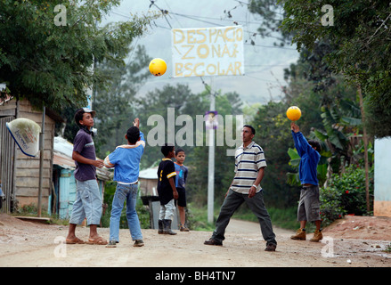 Eine Lehrerin in einem kleinen Dorf spielt Ball mit seinen Schülern unter einen handgemachten Schule Zone Zeichen, Dominikanische Republik Stockfoto