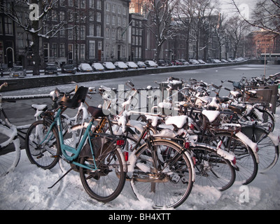 Schneebedeckte Fahrräder neben Kanal Amsterdam vereist Stockfoto