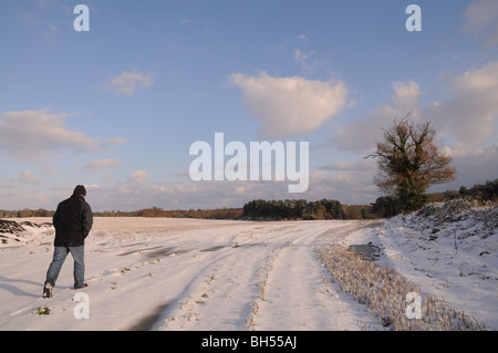 Mann zu Fuß über schneebedeckten Feld. Winter in Tunstall Suffolk Stockfoto