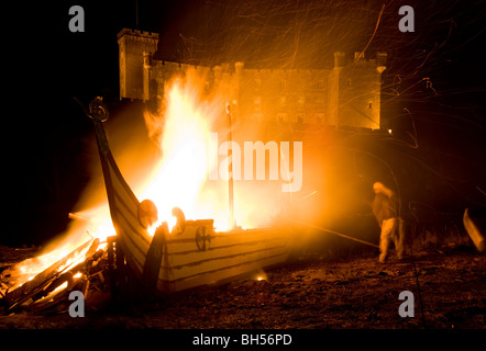 Nach der Party. Dunvegan Castle, Isle Of Skye - Lagerfeuer und das Brennen von einer Nachbildung Wikinger-Langschiff. Stockfoto