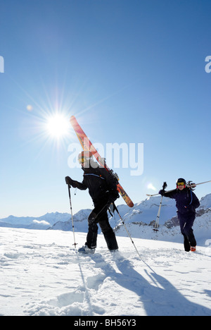 Zwei Skifahrer Wandern und tragen ihre Skier auf Off-Piste-Gelände, Gemsstock, Andermatt, Schweiz Stockfoto