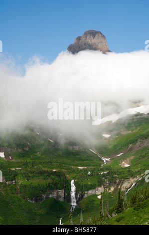 Mt. Reynolds auf Logan Pass ragt über eine Schicht von dicken Wolken und Reynolds Creek Kaskaden unterhalb Stockfoto