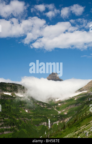 Mt. Reynolds auf Logan Pass ragt über eine Schicht von dicken Wolken und Reynolds Creek Kaskaden unterhalb Stockfoto