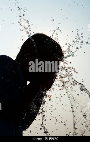 Indischer junge Spritzwasser auf sich Silhouette. Andhra Pradesh. Indien Stockfoto