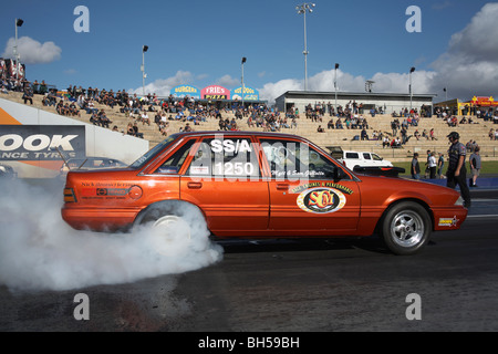 Australischen Holden Commodore Beschleunigungsrennen Auto durchführen einen Burnout um die Hinterreifen vor dem Rennen warm Stockfoto