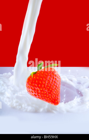 Beeren fallen in der Milch. Isolation auf den roten Stockfoto