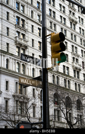 Eine Straßenlaterne an der Ecke Broadway und Wall Street mit Ampeln auf grün. Stockfoto