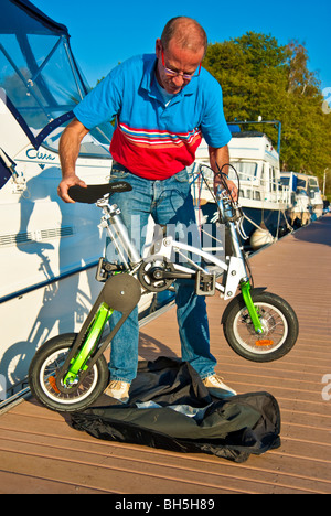 Mann, die Entfaltung einer Mobiky Klapprad auf einem Bootssteg mit Yachten Stockfoto