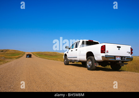 Weißen Dodge Ram 3500 LKW auf abgelegenen Feldweg mit Biker im Hintergrund Badlands Nationalpark, South Dakota, Vereinigte Staaten von Amerika Stockfoto