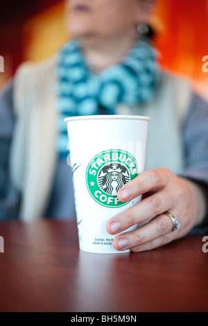 Eine Person an einem Tisch, trinken eine Tasse Kaffee von Starbucks Stockfoto