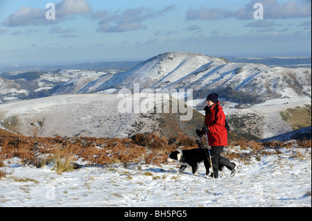 Walker und Hund auf die Shropshire Hügel aus der Long Mynd mit Caer Caradoc bedeckt Schnee uk Stockfoto