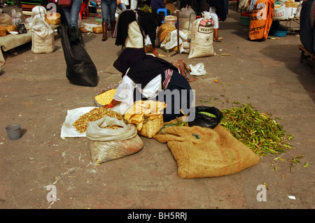 Ecuador, Otavalo, Seitenansicht der Frau sitzt auf dem Boden im Markt neben einem Haufen von frischen grünen Bohnen schälen Sie Stockfoto