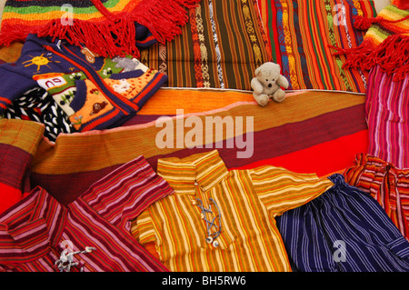Ecuador, Otavalo, Blick auf bunte Textilien (t-Shirts, Hängematte und Wolle Ponchos) mit einem Teddy-Bären in der Mitte Stockfoto